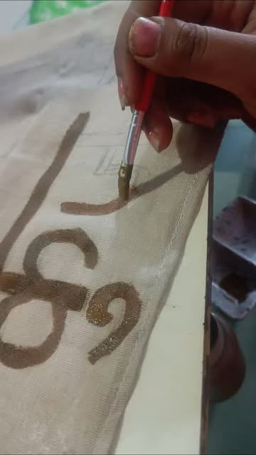 Artisan hand painting sacred Devanagari calligraphy Shree onto wedding silk cloth